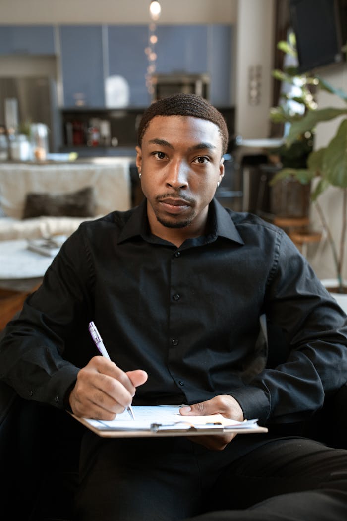 A professional adult man taking notes in a modern office setting, creating a focused atmosphere.